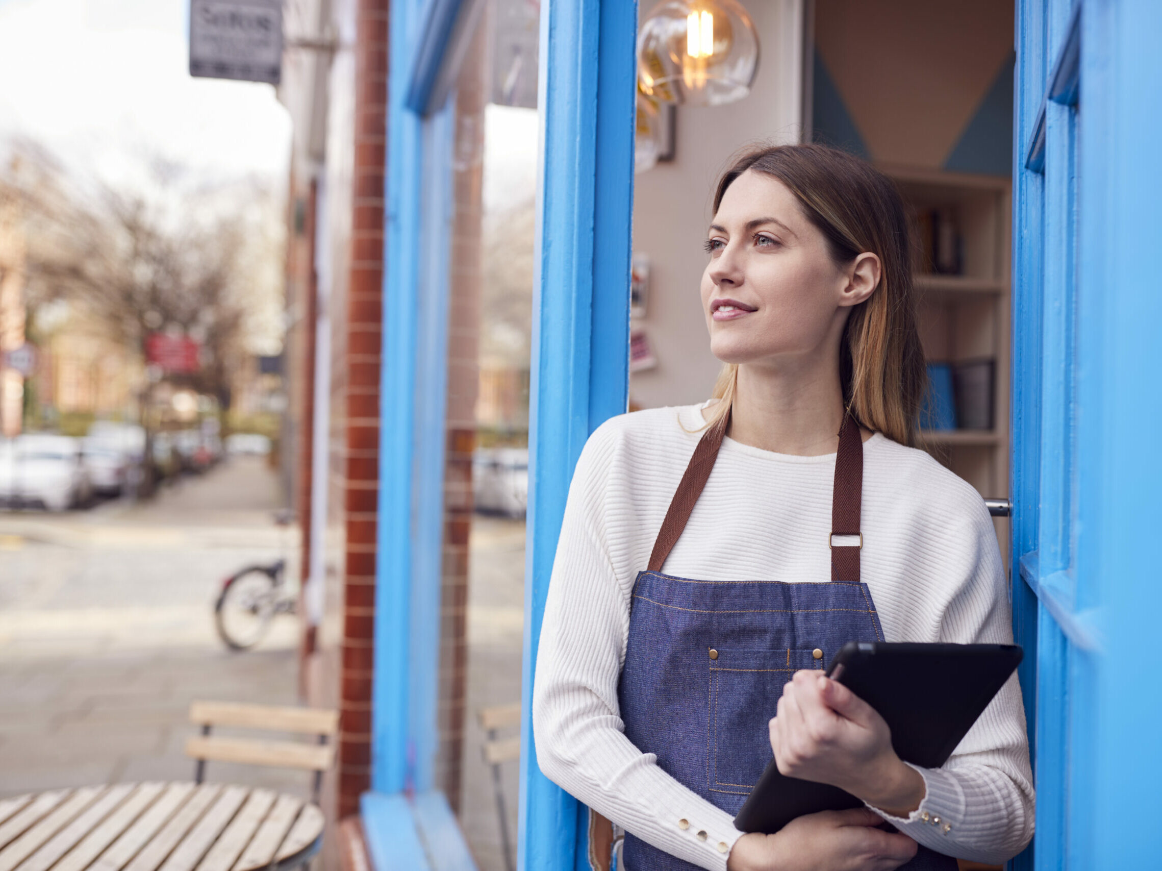 Commerçante devant sa boutique avec une tablette