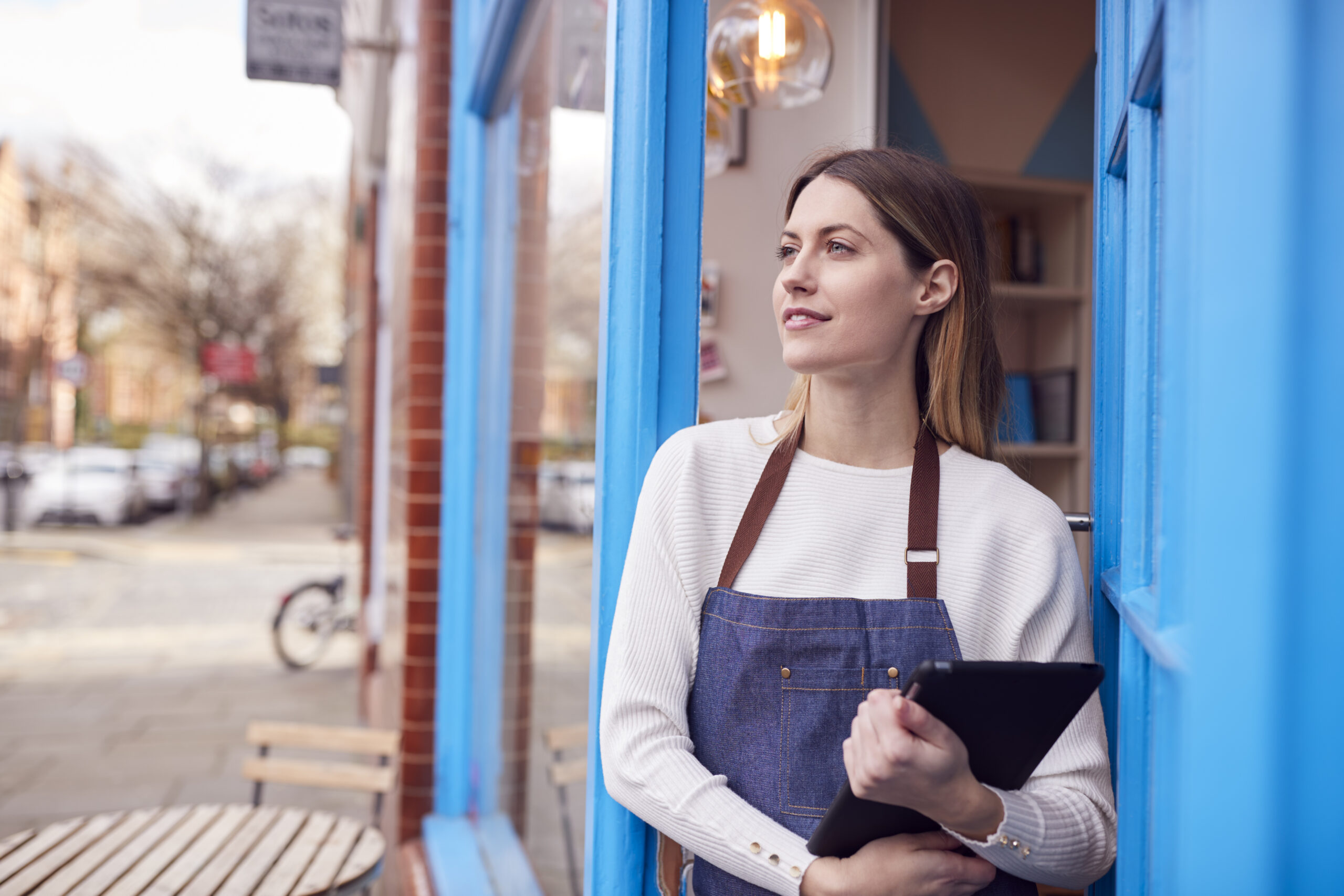 Commerçante devant sa boutique avec une tablette